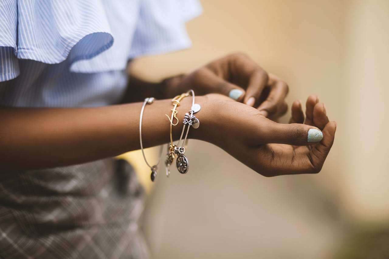 our-services-02 Close-up of a woman's hands adorned with stylish bracelets, showcasing modern fashion jewelry.